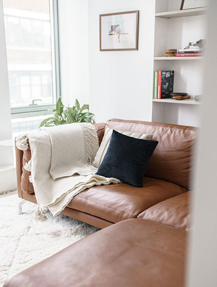 Living room with plush leather couch and soft blankets.