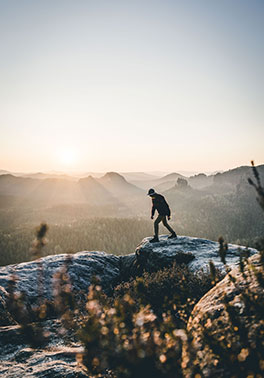 Person climbing on snowy mountain top in the sunlight.